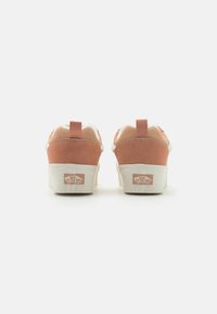 Back view of pink suede sneakers with a white midsole and rubber outsole. Features include a pull tab and logo on the heel.