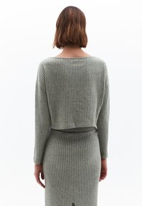 Grå, ribbad stickad tvådelad outfit som består av en kortärmad topp och en matchande kjol med en slits bak för extra detalj.