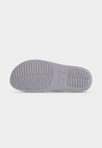 Σόλα γκρι παπουτσιού Crocs με οριζόντια και διαγώνια ανάγλυφα σχέδια για πρόσφυση, που εμφανίζει το μέγεθος και τα σημάδια της μάρκας.