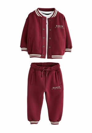 Child's burgundy two-piece outfit with a button-up jacket and elastic waistband pants, both featuring white striped cuffs and brand logo.