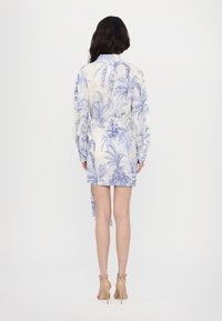Rochie cu imprimeu floral albastru, cu mâneci lungi, talie ajustată și un detaliu legat la spate. Fabricată dintr-un material texturat și ușor.