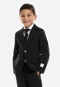 Traje negro con chaqueta de un botón, camisa blanca y corbata negra. Logotipo rojo notable en la manga. Tejido suave, ajuste a medida.