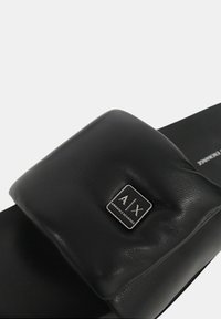 Sandalo scivolato in pelle nera con tomaia imbottita e una placca quadrata con logo. Texture liscia e design della suola piatta per una facile vestibilità.