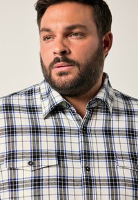 Sprawdzona koszula flanelowa w kolorze białym, czarnym i niebieskim, z kołnierzykiem typu spread, zapinanymi kieszeniami i miękką fakturą.