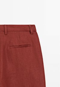 Rudawe spodnie z teksturowanej tkaniny, o slim fit, z szlufkami na pasek i tylną kieszenią z subtelnym przeszyciem.
