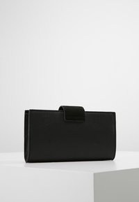 Black wallet with a smooth texture, rectangular shape, and a tab closure. The surface features a subtle pattern. Minimalistic design.