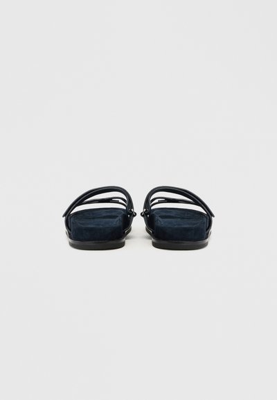 Marineblå sandaler med en ruskindsstruktur, udstyret med en flad sål og tynde vævede remme. Enkel, moderne design der passer til afslappet brug.