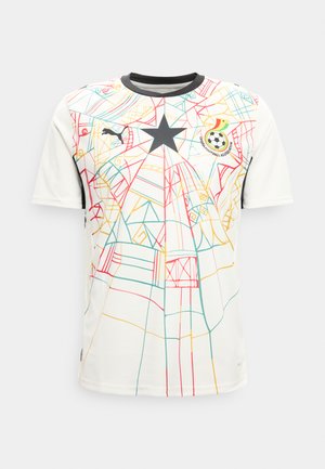 Valge jalgpallimängija särk mitmevärviliste abstraktsete joonemustritega, must täht keskel, Puma logo paremal rinnal ja Ghana Jalgpalliliidu vapp vasakul rinnal.
