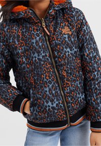 Vadderad jacka med ett mönster av leopardtryck i marinblått, orange och ljusblått. Inkluderar en huva, gulddragkedja och ribbade mudd med färgaccentuerade detaljer.