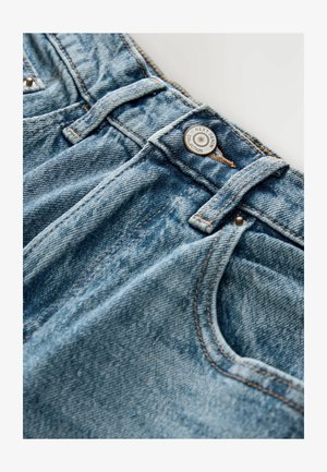 Ljusblå denimjeans med en urtvättad textur. Har en metallknapp och bältesöglor, med synlig sömnad och sidofickor.