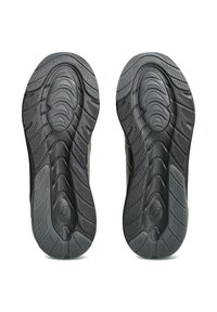 Suelas de zapatillas deportivas de goma negra con patrones texturizados para mayor tracción, que cuentan con ranuras en relieve y un diseño de punta suave y redondeada.