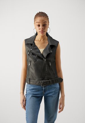 Zwart leren vest met brede revers, asymmetrische ritssluiting aan de voorkant en voorzakken. Heeft een ceintuurtje in de taille en een mouwloos ontwerp.