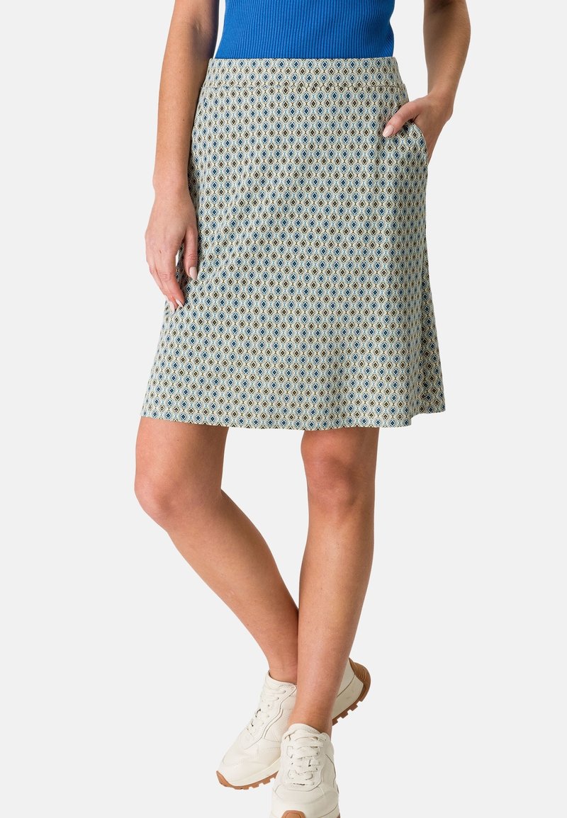 Une jupe mi-longue en tissu à motifs bleu clair et crème, dotée d'une coupe évasée et de poches latérales. Associée à des baskets blanches.