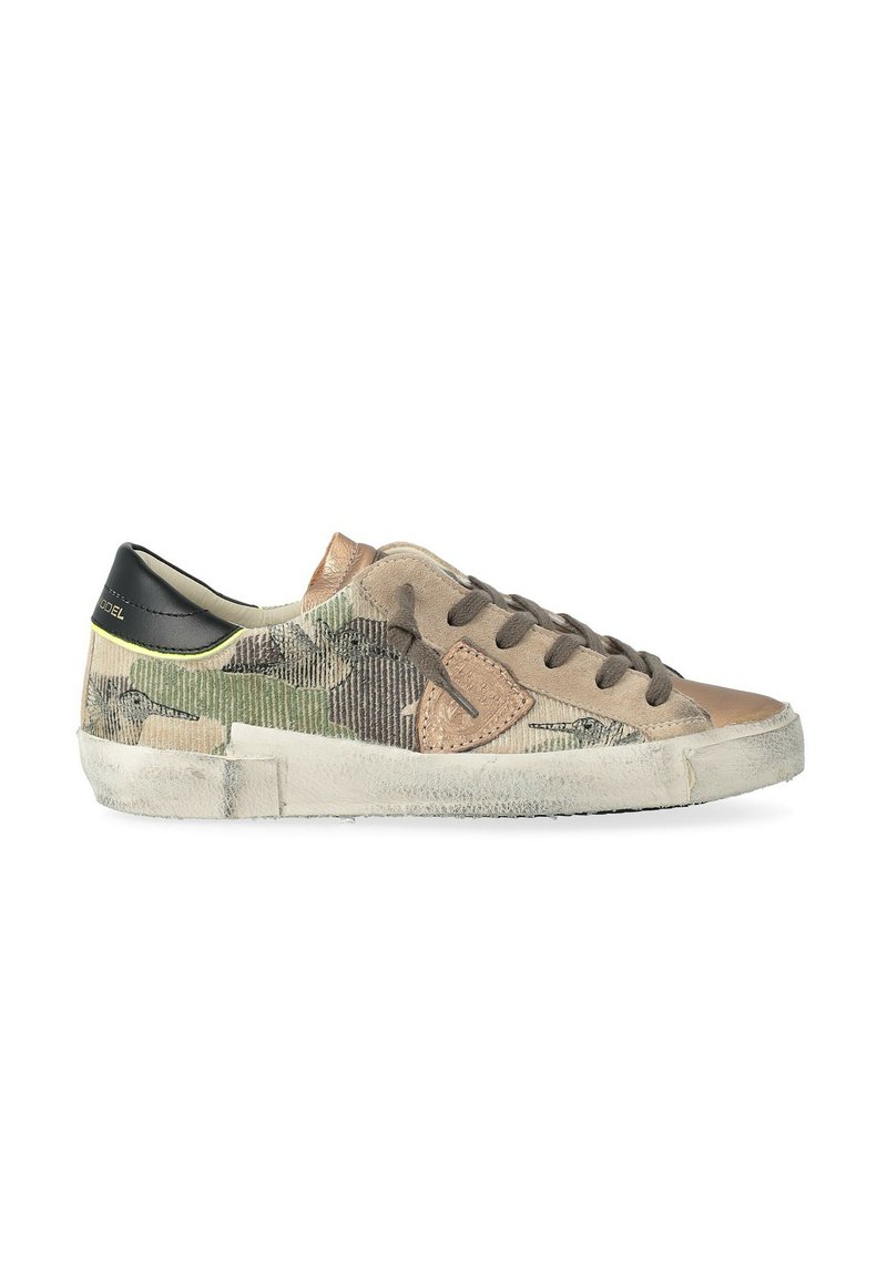 Basket basse avec un motif camo beige, vert et marron, lacets gris foncé, languette en talon noire et semelle blanche usée.