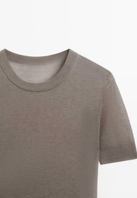 Koszulka z krótkim rękawem, z okrągłym dekoltem, w stonowanym szarym kolorze. Wykonana z gładkiej, lekkiej tkaniny o subtelnej fakturze i czystych krawędziach.