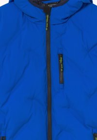 Blauwe waterdichte jas met capuchon, volledige voorkant rits, en een ritszak op de borst met felgroene trekkoorden.