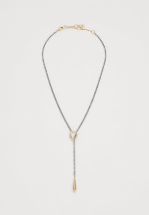 Collana in argento con un centro in anello dorato e un pendente a goccia dorato appeso all'anello su uno sfondo bianco.
