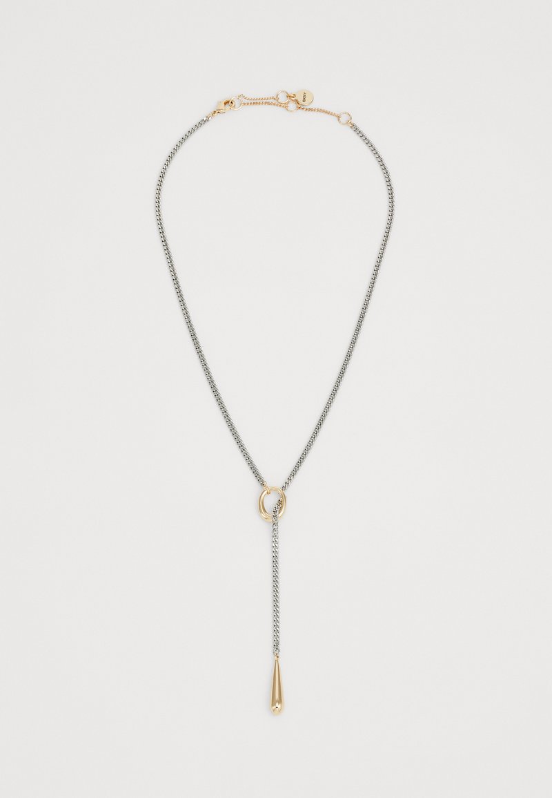 Collier en chaîne argentée avec un pendentif en forme de goutte d'eau doré suspendu à une boucle dorée sur fond blanc.