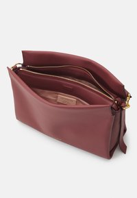 Burgundy színű bőr táska sima, texturált felülettel. Zipperes záródással, dupla rekesszel és arany színű logóval rendelkezik belül.