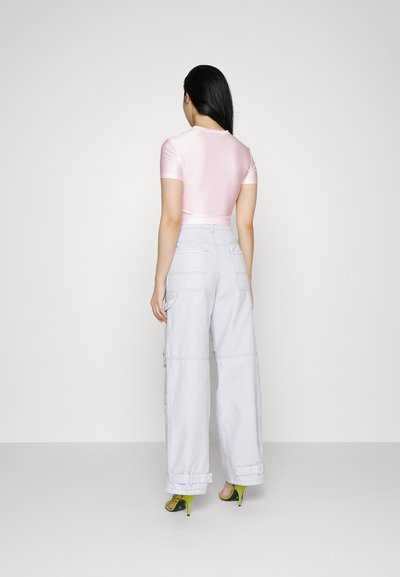 Ρυθμισμένο ροζ σατέν crop top, ανοιχτό γκρι cargo παντελόνι με μεγάλες τσέπες και φωτεινά πράσινα ψηλοτάκουνα παπούτσια. Απλή πίσω όψη.