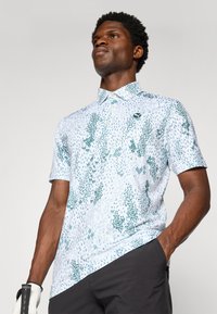 Short-sleeve polo shirt featuring a white base with green floral patterns, a pointed collar, and a logo accent on the chest.