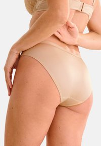Mutande senza cuciture beige con tessuto morbido e liscio e copertura minima. Presenta un design a vita bassa e una cintura elastica per il massimo comfort.