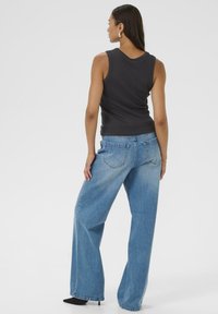 Black fitted tank top and wide-leg blue jeans with a light wash, featuring back pockets and a casual style. Smooth texture and simple design.