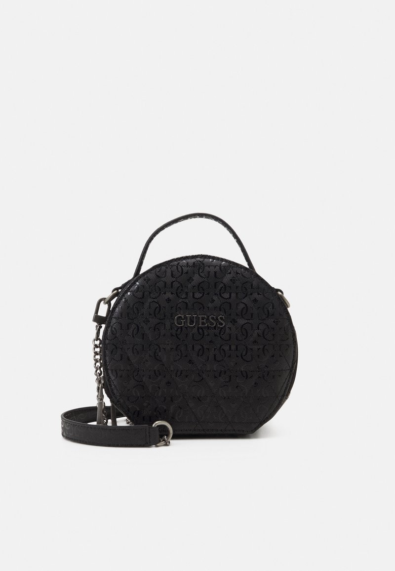 Sac à main rond noir Guess avec motif monogramme, poignée supérieure et bandoulière amovible sur fond blanc.