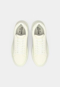 Pair of cream-colored Jack & Jones sneakers with white laces, viewed from above on a plain white background.