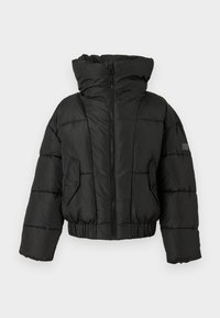 Jachetă puffer neagră cu guler înalt, fermoar frontal complet, mansete elastice și benzi. Dispune de secțiuni matlasate și o buzunar lateral.