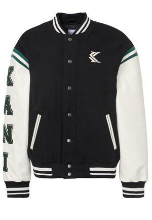 Veste varsity noire et blanche avec fermeture à boutons, col et poignets rayés, accents verts et lettrage sur la manche droite.