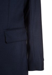 Granatowa marynarka dopasowana z fakturowanej tkaniny, z jedną kieszenią na piersi oraz strukturalnym krojem ramion.