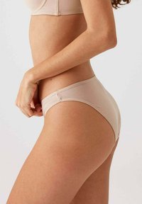 Bikini slip in lichtbeige, gemaakt van een gladde stof met een aansluitend ontwerp. Het heeft een lage taille en minimale stikdetails langs de tailleband.