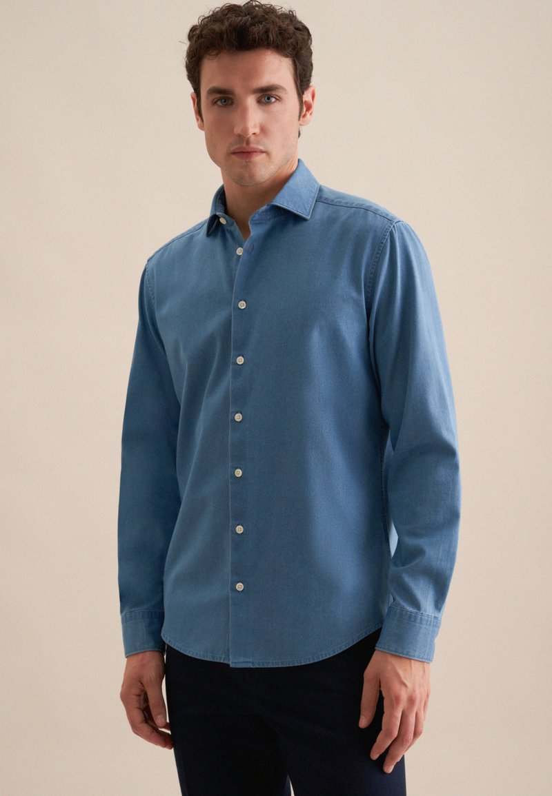 Lichtblauw denim overhemd met lange mouwen, een button-down kraag en een gebogen zoom. Voorzien van witte knopen langs het middenvoor.