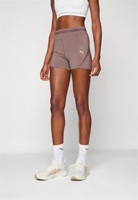 Shorts sportivi da donna Puma in marrone chiaro, con un design aderente, una cintura larga e un piccolo logo bianco sul lato.