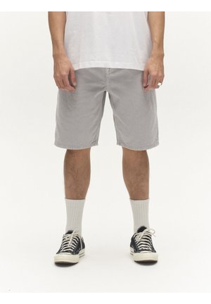 Mees kannab heledat halli põlvpikkust lühikest pükst, valgeid crew-sokke, must-valgeid vabaajajalatsid ja valget t-särki, seisab valgel taustal.