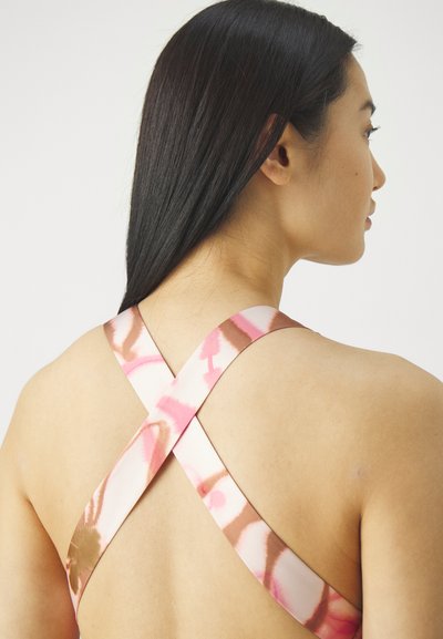 Costume da bagno con schiena incrociata in un motivo tie-dye rosa e marrone, con spalline larghe e una texture del tessuto liscia. Vista ravvicinata della parte posteriore.