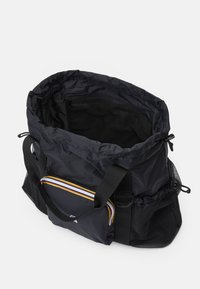 Svart nylon treningspose med bred åpning, justerbare stropper, nettinglomme på siden, og en avtakbar frontlomme med fargerike striper.