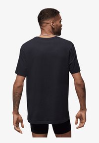 Black cotton t-shirt with a relaxed fit, short sleeves, and a crew neckline. Features visible stitching and a smooth texture.