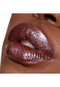 Dybe bærfarvede læber med en glansfuld, glitrende finish. Teksturen er glat med subtile højdepunkter og definerede læbekonturer.