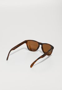 Ochelari de soare în stil țestoasă cu lentile maronii. Design cu ramă pătrată și brațe elegante. Logo-ul brandului pe tâmple, finisaj mat, stil casual.