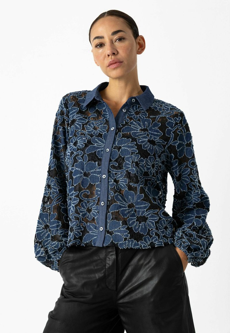 Zila ziedu izšuvuma blūze ar džinsa apkakli un pogām. Puscaurspīdīgs materiāls, garas balonu formas piedurknes un brīvs piegriezums.