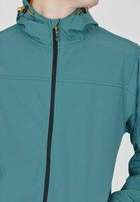 Tealfärgad jacka med dragkedja fram, huva och svarta dragkedjedetaljer. Har orangea accentdragningar och textilmaterial med textur.