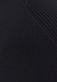 Close-up of black knitted fabric with diagonal and vertical ribbed patterns.