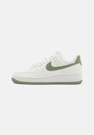 Vita Nike Air Force 1-sneakers med gröna detaljer, med övre del i slätt läder, rund tå och texturerad gummisula.