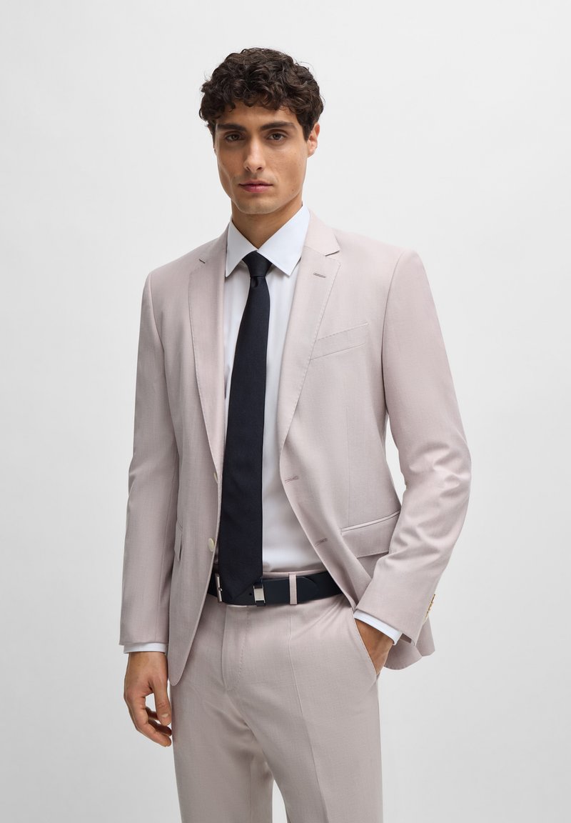 Blazer rosa claro com calças a condizer, camisa branca e gravata escura. Apresenta um design ajustado, textura suave e detalhes em costura subtil.
