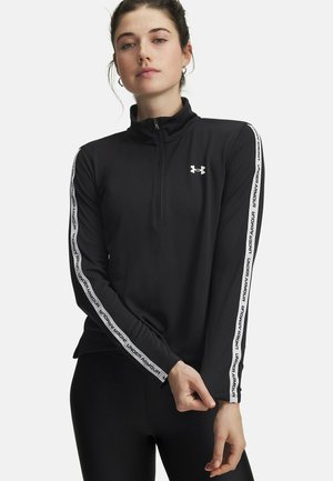 Zwart atletisch top met lange mouwen en een ritssluiting bij de hals, met witte "Under Armour" tape langs de mouwen en een aansluitend ontwerp. Zachte textuur.