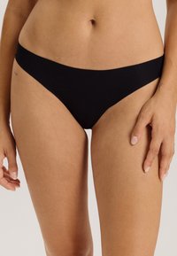 Bas de bikini en coton noir avec une taille basse, une couverture minimale et une texture lisse. Présente un design simple sans embellissements.