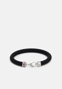 Bracciale in pelle intrecciata nera con hardware in argento, chiusura a granchio e un accento a righe vicino alla chiusura. Forma rotonda, design flessibile.