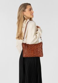 Borsa a tracolla in pelle intrecciata marrone con forma rettangolare, una corta tracolla e dettagli testurizzati. Il design presenta cuciture in vista.